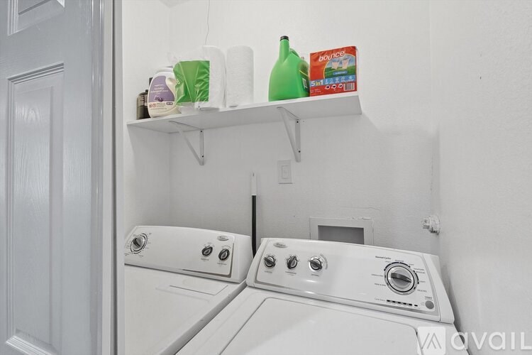 A white washing machine with a shelf above it.