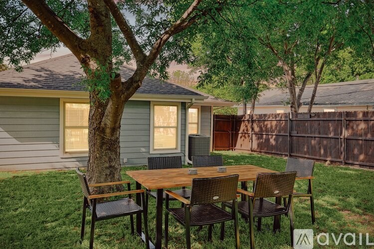 A backyard with a table and chairs under a tree.