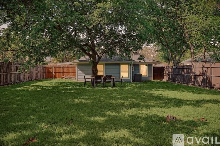 A backyard with a tree and a house in the background.