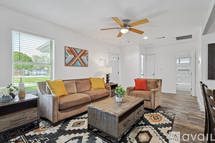 A living room with a brown couch, a wooden coffee table, and a ceiling fan.