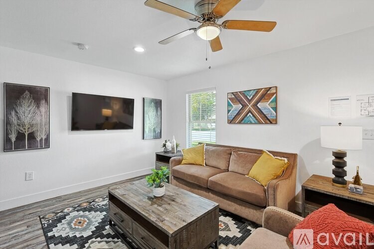 A living room with a brown couch, a wooden coffee table, and a ceiling fan.