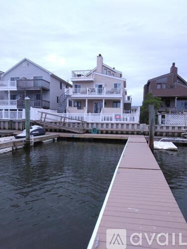 A dock with a boat and houses in the background.