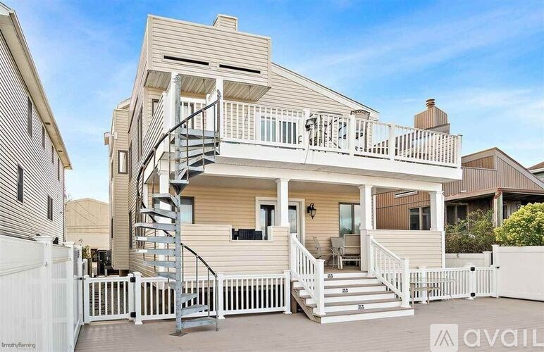 A modern house with a white fence and a spiral staircase leading to the upper floor.