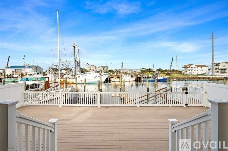 A wooden deck overlooks a harbor with boats and buildings.