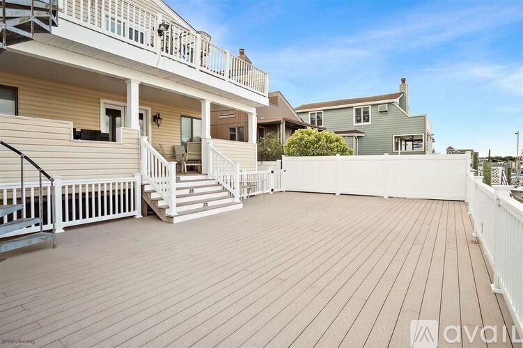 A wooden deck with a white railing and a house in the background.
