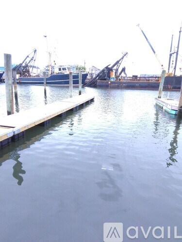 A dock with boats and cranes in the background.