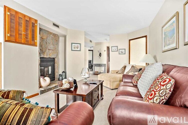 A living room with a red couch and a stone fireplace.
