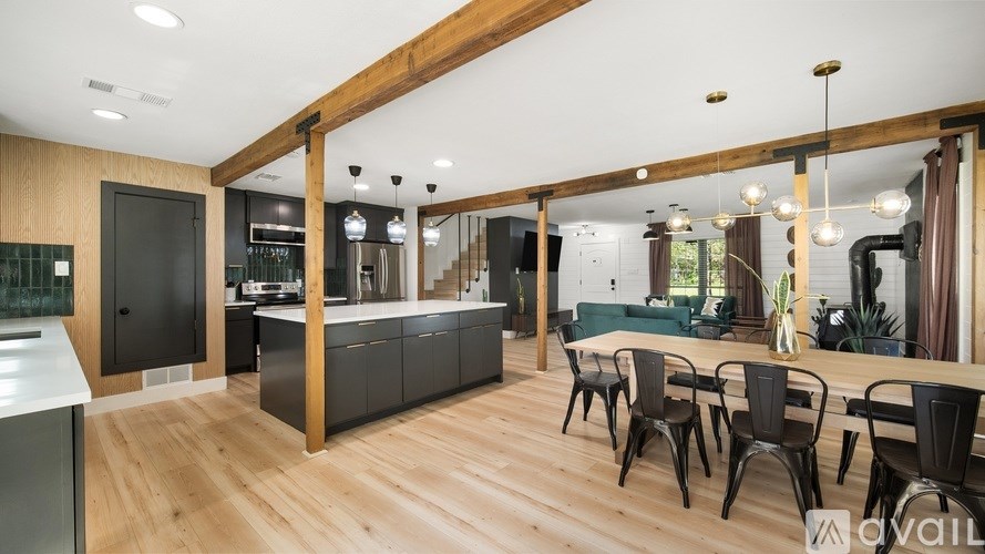 A modern kitchen with wooden floors and black chairs.