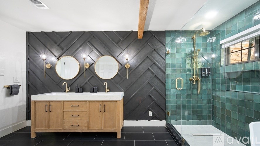 A modern bathroom with a wooden vanity and a black tiled wall.