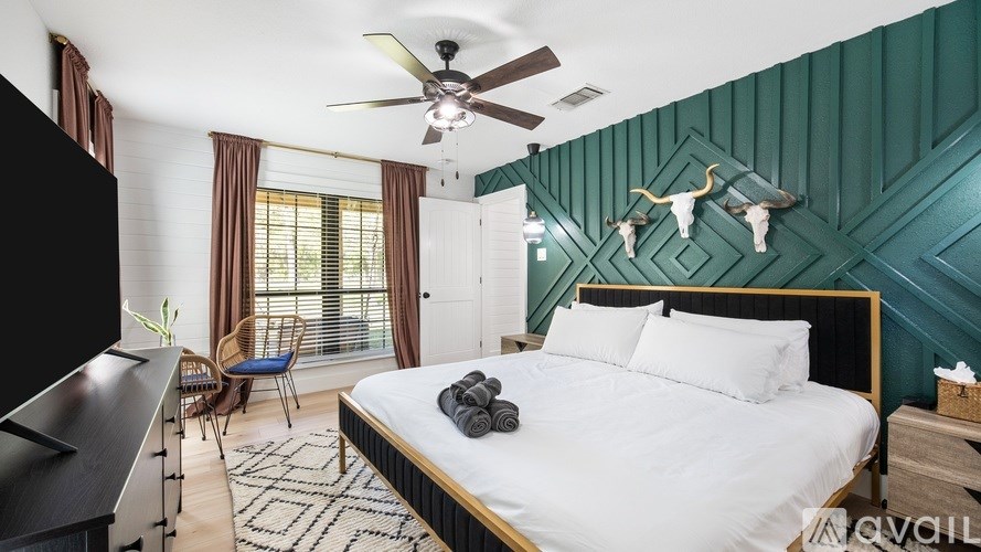 A bedroom with a bed, a chair, and a ceiling fan.
