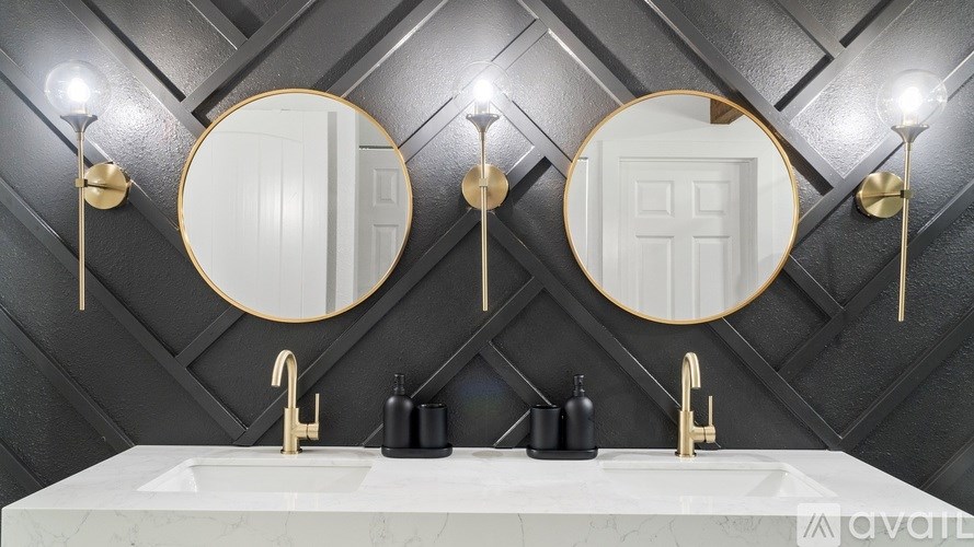 A bathroom with a marble countertop and two round mirrors above sinks.