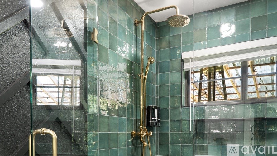 A shower with a gold shower head and a gold handle.