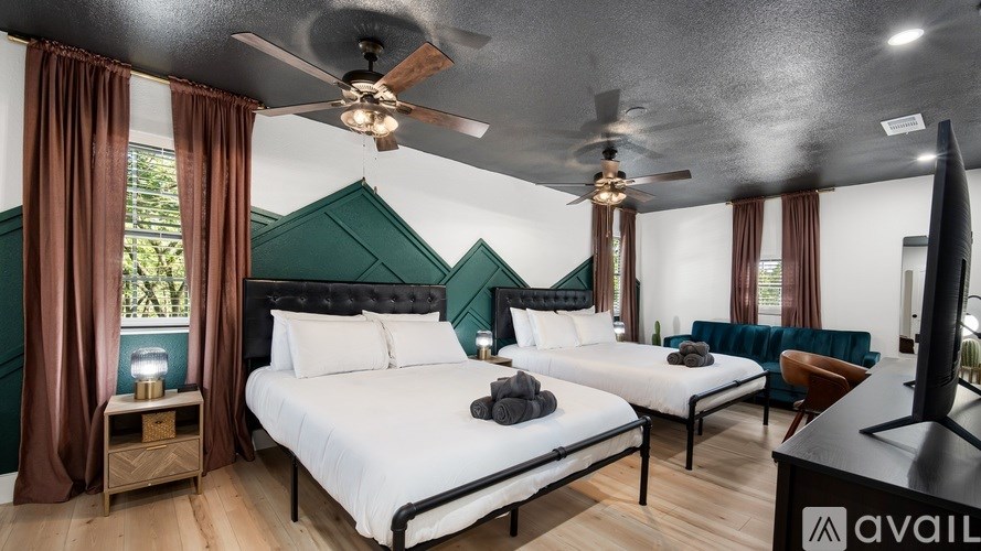 A bedroom with two beds, a ceiling fan, and a television.