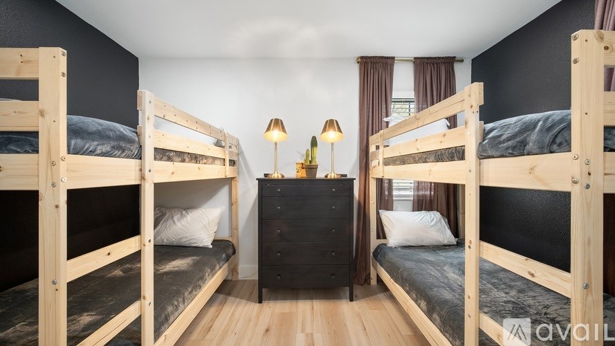 A room with bunk beds and a nightstand with lamps.