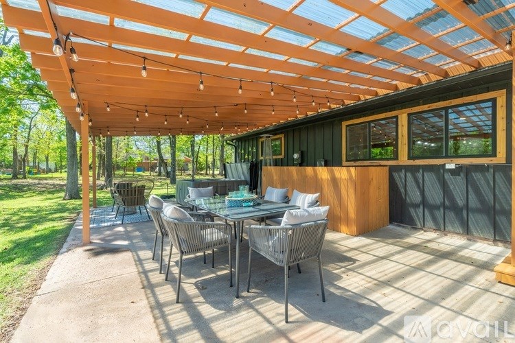 A patio with a table and chairs under a wooden pergola.