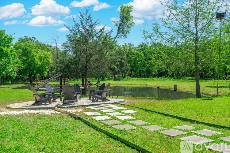 A park with a pond, trees, and a stone path.