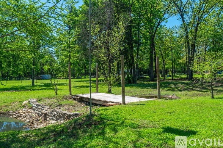 A wooden deck is surrounded by trees in a grassy area.