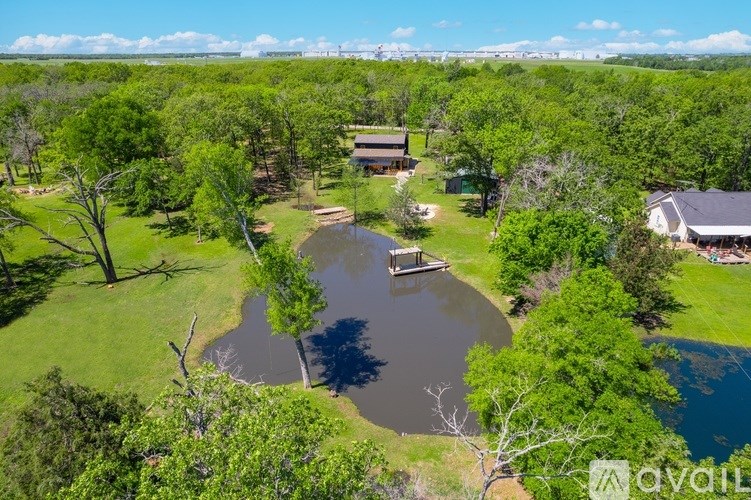 A bird's eye view of a house surrounded by trees and a pond.
