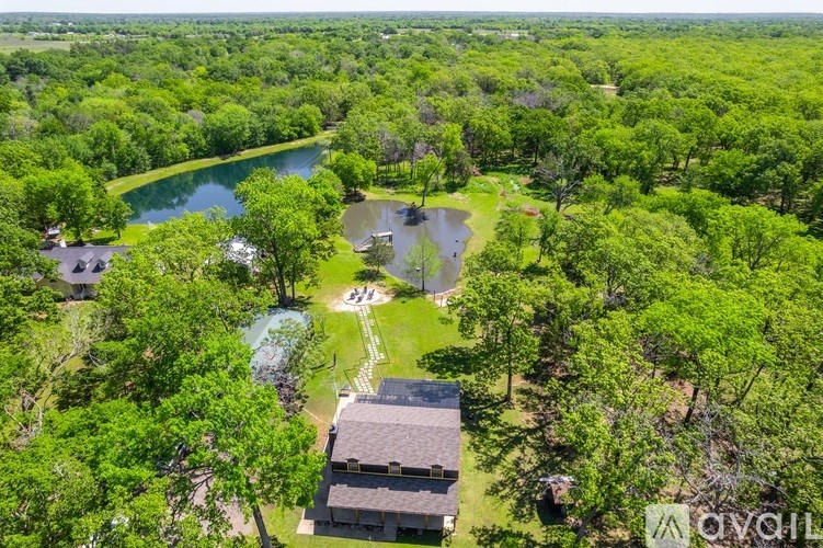 A bird's eye view of a house surrounded by trees and a lake.