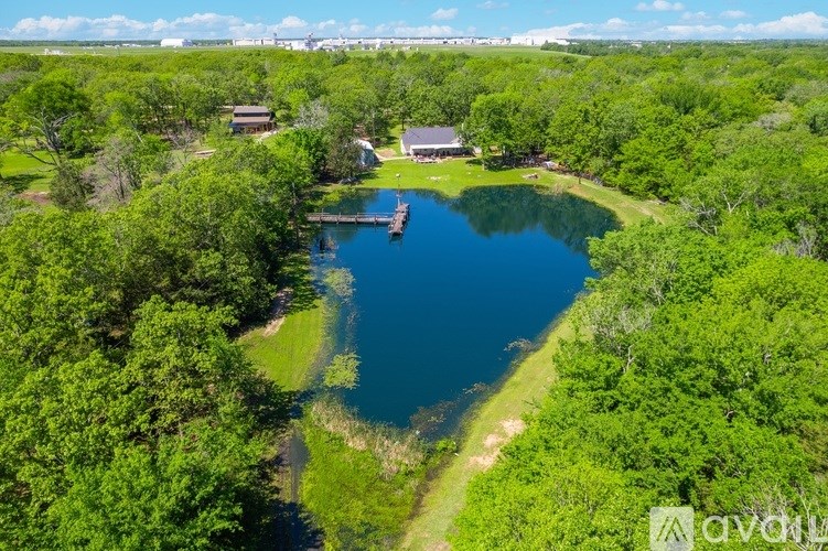 A serene landscape with a lake, greenery, and a small building.