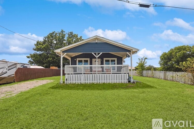 A house with a blue roof and a white picket fence is for sale.