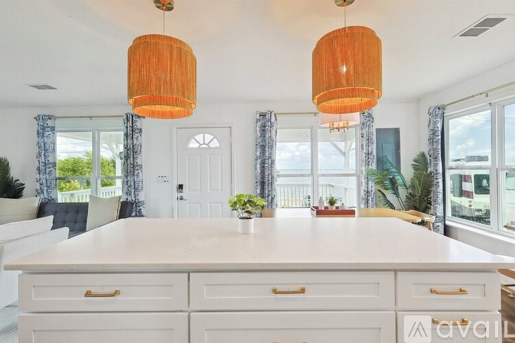 A kitchen with a large island and two hanging lights.