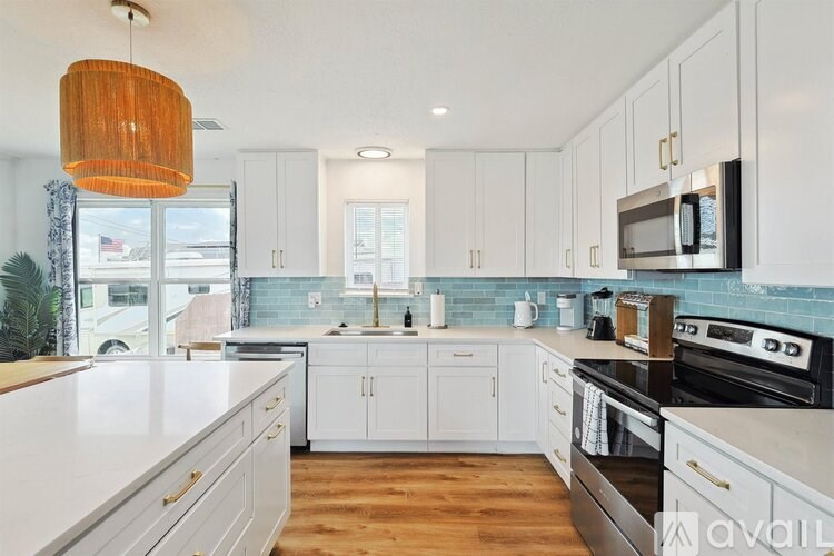 A kitchen with white cabinets and a wooden floor.