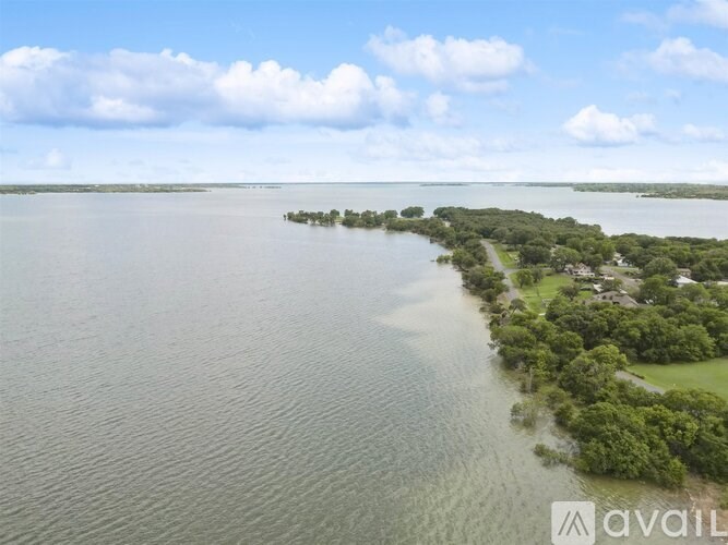 A large body of water surrounded by greenery and a cloudy sky.