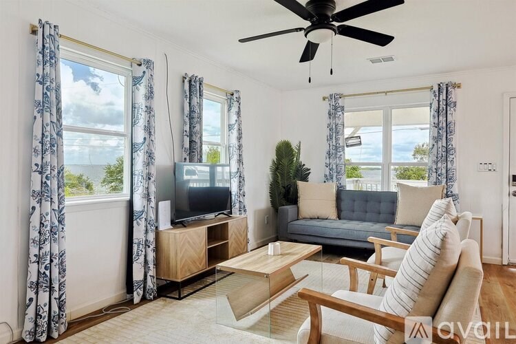 A living room with a grey couch, a wooden coffee table, a television, and a ceiling fan.