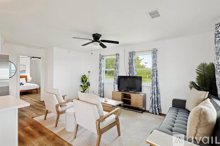 A living room with a television, a sofa, and a fan.