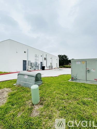 A white building with a green trash can in front of it.