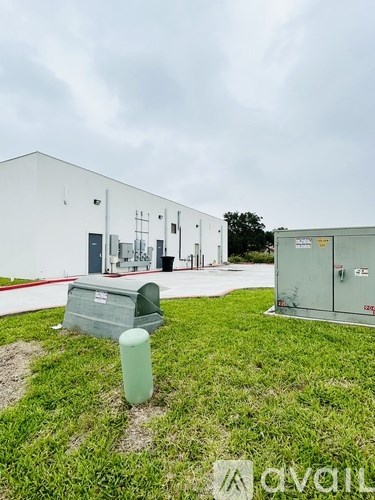 A white building with a green trash can in front of it.