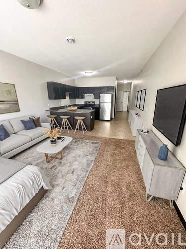 A living room with a grey sofa, a white coffee table, and a television on the wall.