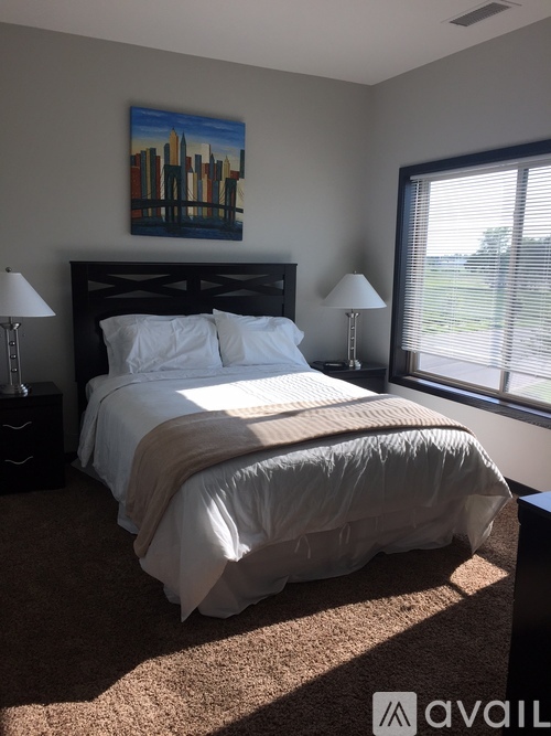 A bedroom with a large bed and a painting on the wall.