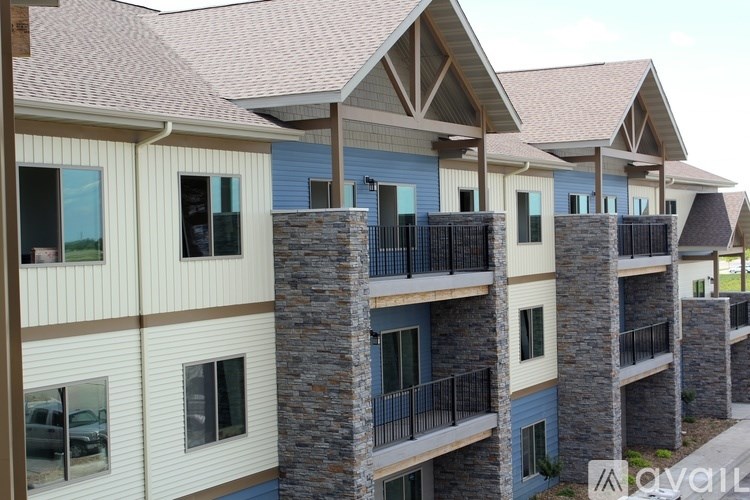 A row of modern apartment buildings with balconies and stone pillars.