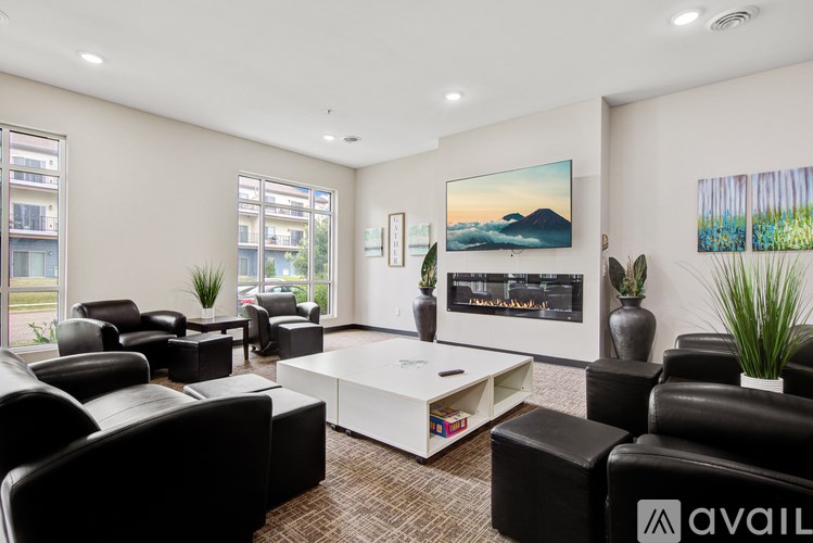 A living room with black leather furniture and a large painting on the wall.