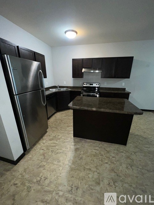 A kitchen with a black countertop and a stainless steel refrigerator.