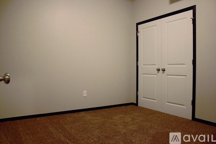 A room with a white door and a brown carpet.