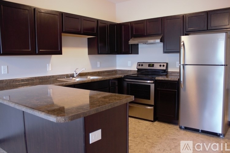 A kitchen with dark brown cabinets and a granite countertop.