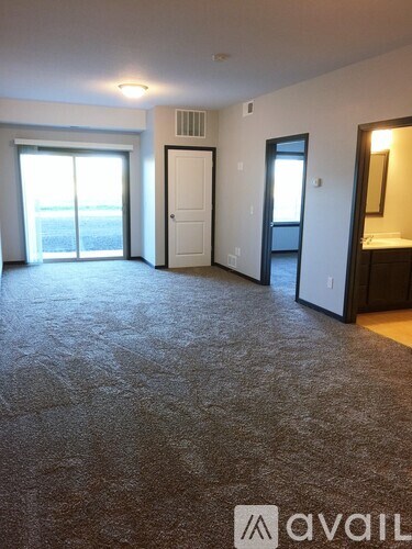 A carpeted room with a door and a window.