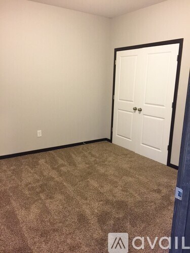 A room with a carpeted floor and a white door.