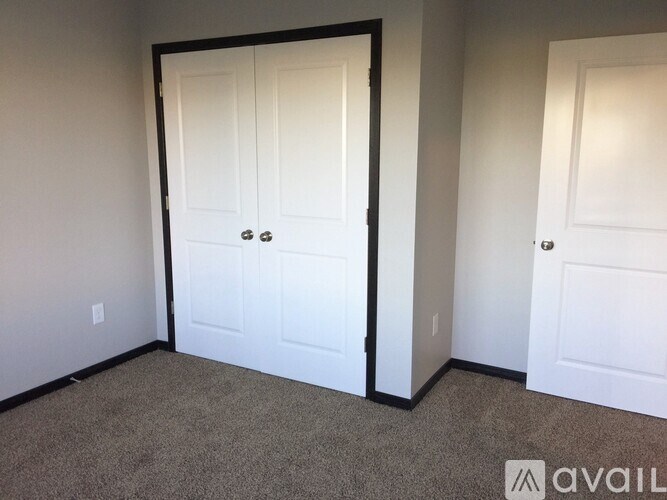 A room with a white door and a carpeted floor.