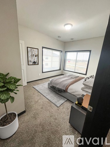 A bedroom with a bed, a plant, and a picture on the wall.