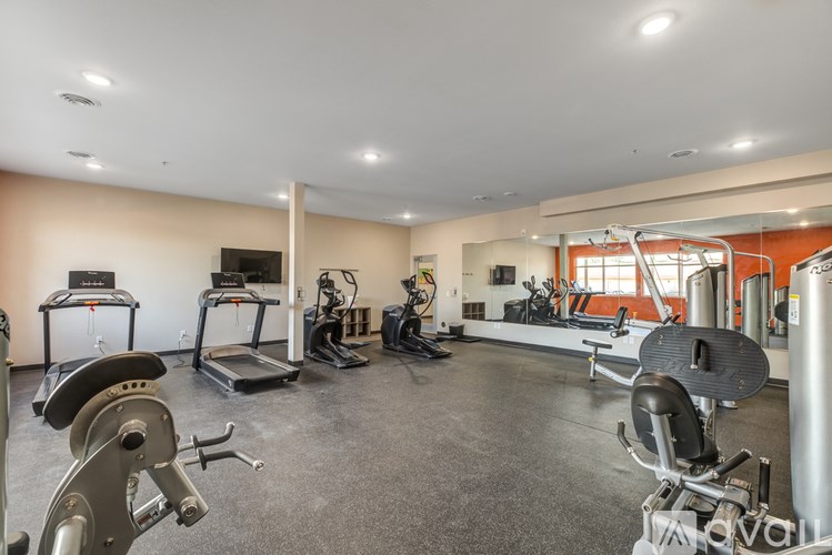 A spacious gym with a variety of equipment including treadmills, stationary bikes, and weight machines.