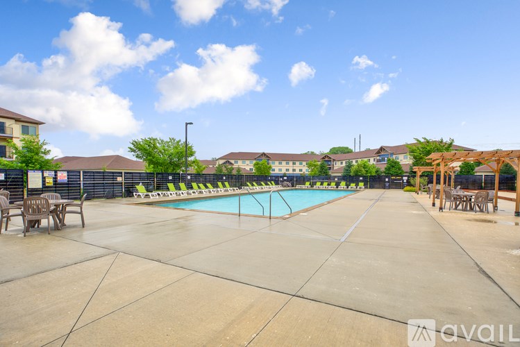 A large outdoor swimming pool surrounded by a concrete patio and lounge chairs.