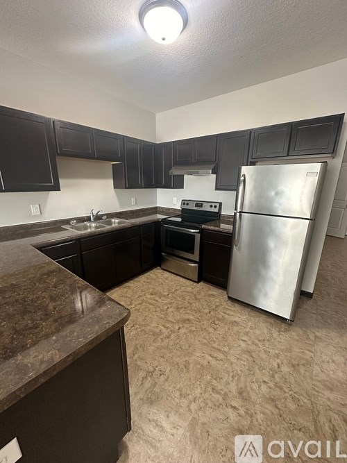 A kitchen with a refrigerator, oven, and sink.