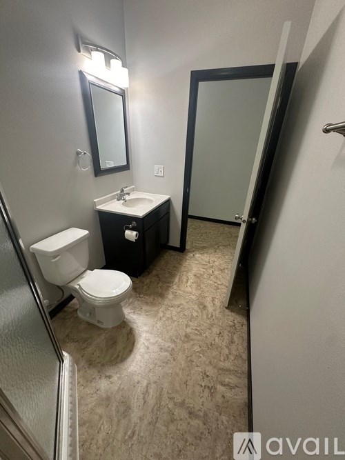 A bathroom with a toilet, sink, mirror, and a door.