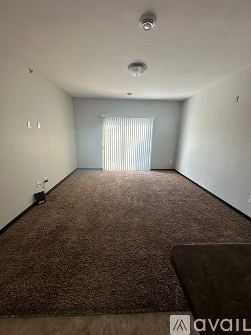 A room with a carpeted floor and a window with blinds.