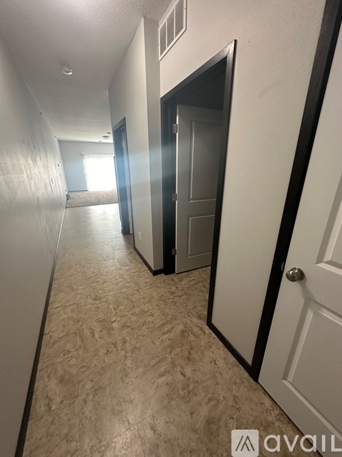 A hallway with a carpeted floor and white walls.