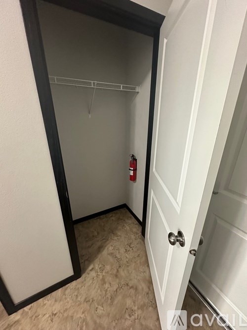 A white door with a black frame is open to a hallway with a fire extinguisher on the wall.